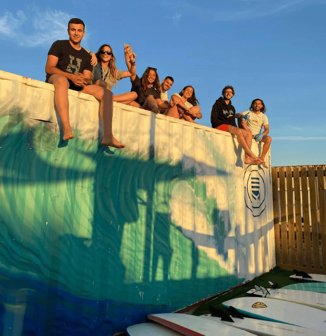 A group of young people sitting on a container of a surf school